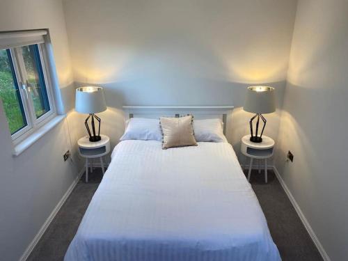 een slaapkamer met een groot wit bed met 2 lampen bij The Lodge in Royal Tunbridge Wells