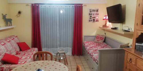 ジェラールメにあるLes Dryades L'Epicéaのソファと赤いカーテンが備わる小さなお部屋です。
