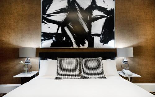 a bedroom with a bed with two lamps and a painting at Ameritania at Times Square in New York