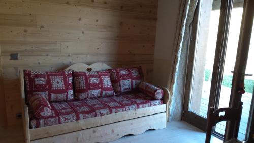 ein Sofa mit Kissen in einem Zimmer mit Fenster in der Unterkunft Votre appartement savoyard de 32m2 à proximité de la télécabine pour skier les 3 Vallées ! in Villarlurin