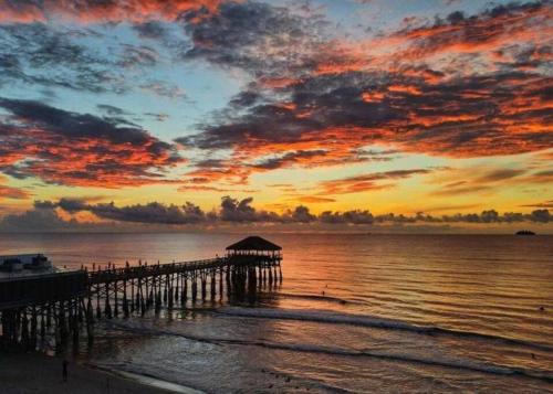 a pier on the beach with a sunset at Luxury 2/2 private oasis w/Hot Tub walk to Beach in Cape Canaveral