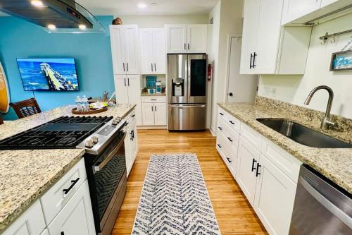 a kitchen with white cabinets and a stainless steel refrigerator at Luxury 2/2 private oasis w/Hot Tub walk to Beach in Cape Canaveral