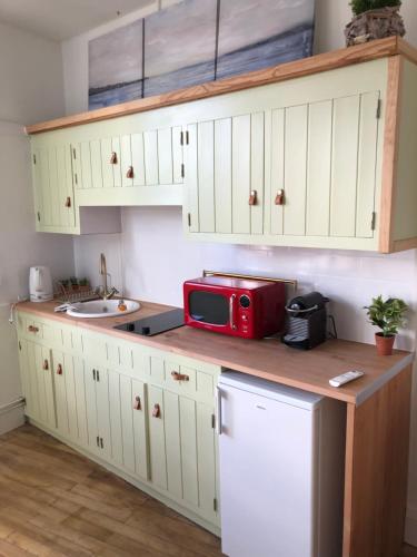 - une cuisine avec des placards blancs et un four micro-ondes rouge dans l'établissement Juste au dessus de la Veules, à Veules-les-Roses