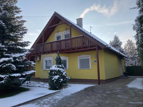 a yellow house with a deck on top of it at Príma Vendégház in Tiszakécske