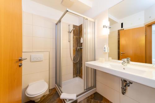 a bathroom with a shower and a toilet and a sink at Hotel Bördehof in Barleben