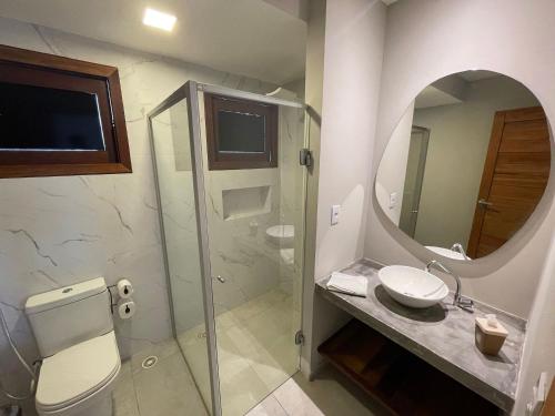 a bathroom with a toilet and a sink and a mirror at Pousada Recanto Nalu - Quarto à Vista in Pipa