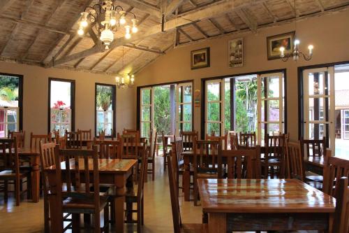 a dining room with tables and chairs and windows at Pousada da Sirlei in Tiradentes