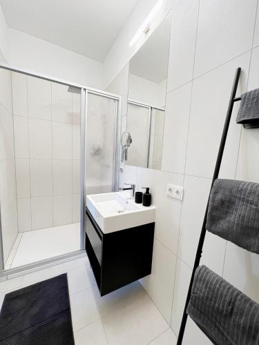 ein weißes Bad mit einem Waschbecken und einer Dusche in der Unterkunft Sissi West in Wien