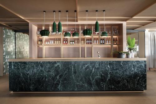 a bar with a black marble counter and green pendant lights at Eden Roc Resort - All Inclusive in Kallithea Rhodes
