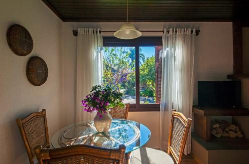 uma sala de jantar com uma mesa de vidro com um vaso de flores em Hotel Canto Verde em Gramado