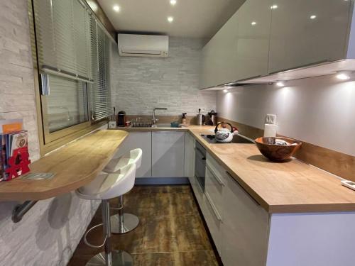 una cucina con mobili bianchi e un piano di lavoro in legno di Studio tout confort au calme avec jardin proche Cannes a Le Cannet