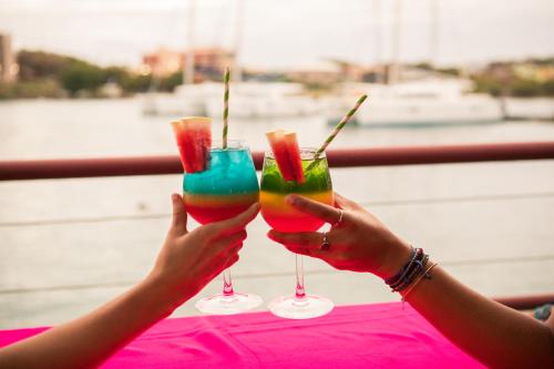 two hands holding up two glasses with drink at True Blue Bay Resort in Saint Georgeʼs