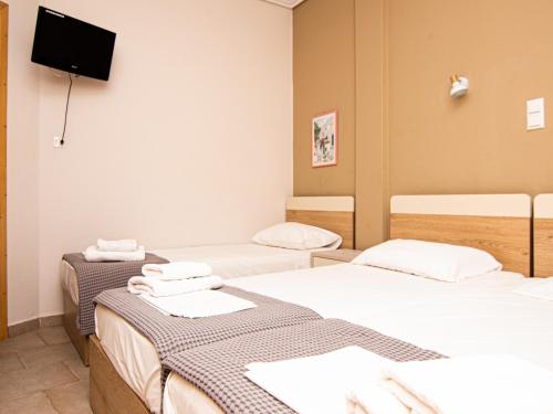 um quarto com 3 camas e uma televisão de ecrã plano em Afrodite Beach em Neoi Poroi