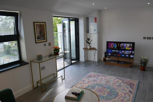a living room with a tv and a table at Lovely & Spacious 2-Bedroom Apartment with Balcony and Free Parking in Oxford