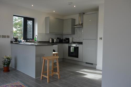 a kitchen with white cabinets and a stool in it at Lovely & Spacious 2-Bedroom Apartment with Balcony and Free Parking in Oxford
