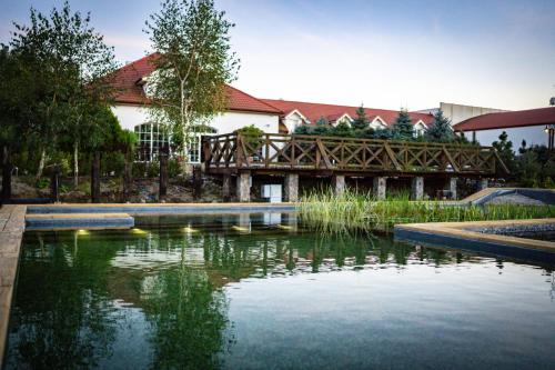 a bridge over a pond in front of a building at Santa Natura Resort & SPA in Nowa Wieś