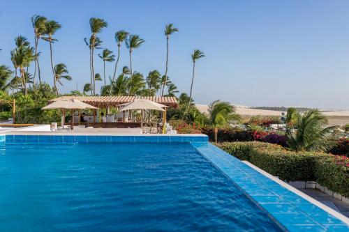 a swimming pool in front of a resort with palm trees at Pousada Chez Toi in Jericoacoara