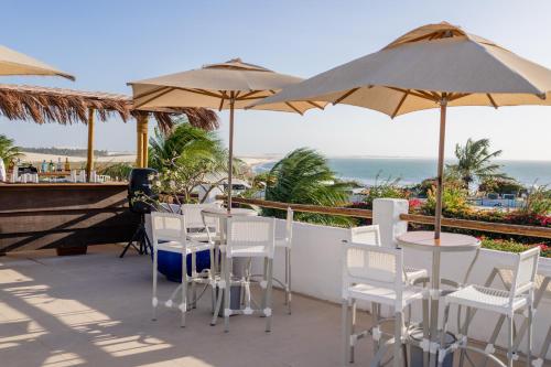 a patio with tables and chairs and umbrellas at Pousada Chez Toi in Jericoacoara