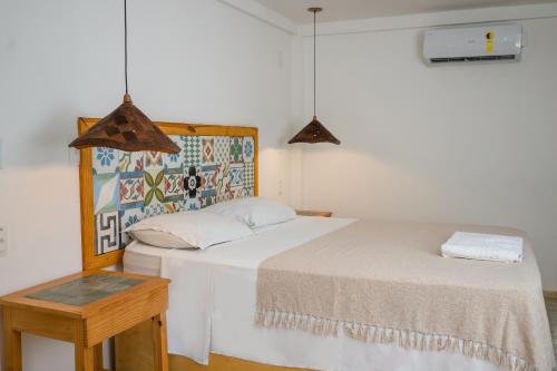 a bedroom with a white bed and a table at Pousada Chez Toi in Jericoacoara