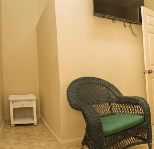 una silla de mimbre en una esquina con TV en la pared en Mariner Motel, en Bridgetown