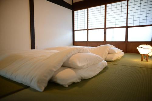 1 cama con sábanas blancas en una habitación con ventanas en Guest House Tamaki - Vacation STAY 53922v en Furuichi