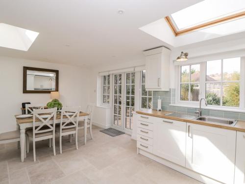 a kitchen with white cabinets and a table with chairs at Fisherbridge Cottage in Weymouth