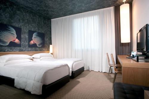 Habitación de hotel con cama, escritorio y TV. en Sea Art Hotel en Vado Ligure