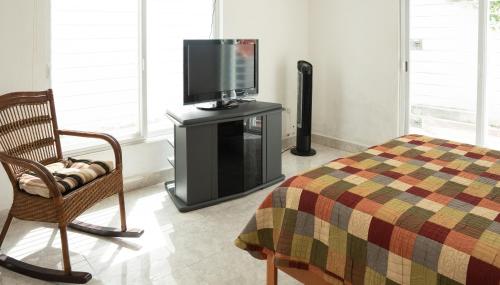 a bedroom with a bed and a tv and a chair at Casa Familiar para hospedaje privado en Mérida in Mérida