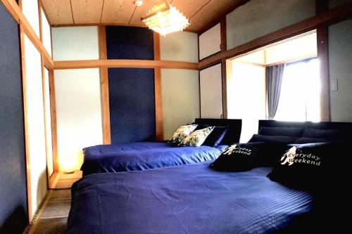 IKI HOUSE KATSUMOTOURA - Vacation STAY 13495v في إكي: غرفة نوم بسريرين مع شراشف زرقاء ونافذة