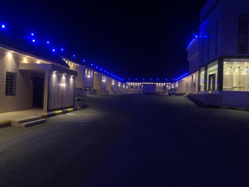 an empty parking lot at night with blue lights at منتجع ركام للوحدات السكنية in Ad Darb