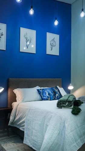 a blue bedroom with a bed with a blue wall at 1-bedroom apartment with secure basement parking in Stellenbosch