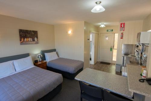 um quarto de hotel com duas camas e uma cozinha em Howick Motor Lodge em Auckland