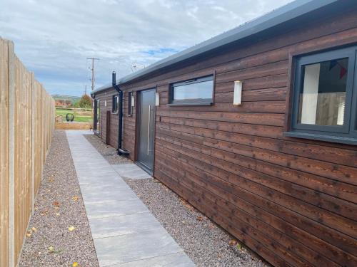 a wooden fence next to a house with a sidewalk at The Potting Shed in Bredon