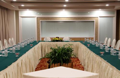 a large meeting room with a long table with chairs and a screen at Grand Riverview Hotel in Kota Bharu