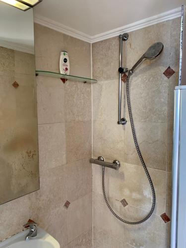 La salle de bains est pourvue d'une douche avec un masque mural. dans l'établissement Home Sweet Home Claridge Champs-Elysées, à Paris