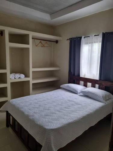1 dormitorio con 1 cama con cortinas azules y ventana en Pura vida apartament 5 min near aiport NO PARKING SITE, en Alajuela