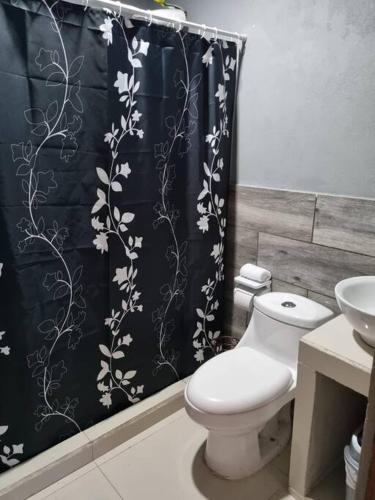 a bathroom with a toilet and a shower curtain at Pura vida apartament 5 min near aiport NO PARKING SITE in Alajuela