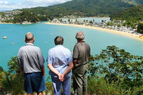 three men standing on a hill looking at a beach at Orinoco Country Retreat in Ngatimoti