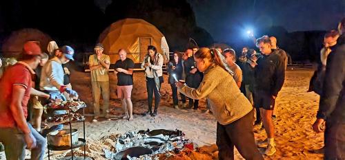 a group of people standing around a camp fire at Hasan Zawaideh luxury camp 2 in Wadi Rum