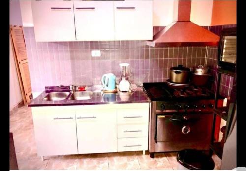 uma cozinha com armários brancos e um forno com placa de fogão em El Carmelo em Santiago del Estero