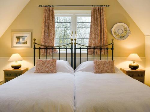 Westhampnett的住宿－Goodwood Coach House，一间卧室设有两张床和窗户。