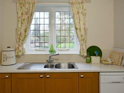 Westhampnett的住宿－Goodwood Coach House，厨房设有水槽和窗户。