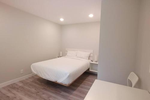 a white bedroom with a bed and a mirror at Beautiful 2 bedroom + office basement suite in Calgary