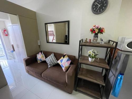 a living room with a couch and a clock on the wall at A&B Condo with Netflix at SMDC Wind Residences in Tagaytay