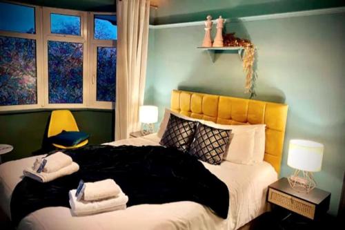 a bedroom with a large bed with a yellow headboard at 3 Bedroom House -Sleeps 6- Big Savings On Long Stays! in Canterbury