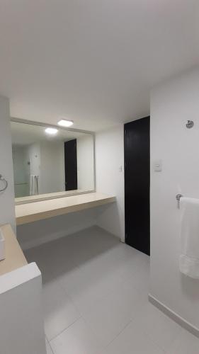 a white bathroom with a mirror and a sink at Vallclaire Suites in Barranquilla