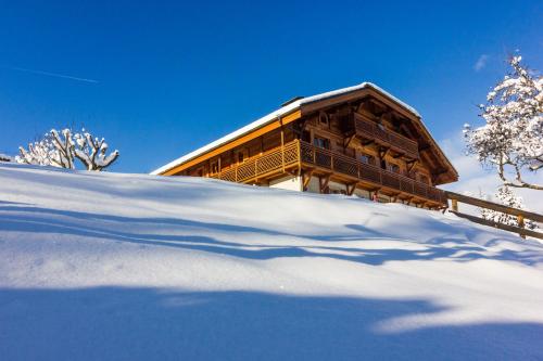 a building on a snowy hill with a shadow in the snow at Hôtel Restaurant La Ferme de Cupelin in Saint-Gervais-les-Bains