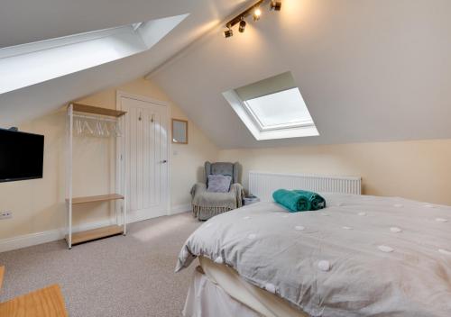 1 dormitorio con 1 cama, TV y silla en Oaktree Cottage, en Amroth
