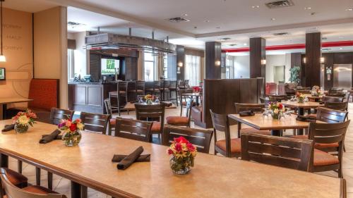 a restaurant with tables and chairs with flowers on them at Holiday Inn North Quail Springs by IHG in Oklahoma City
