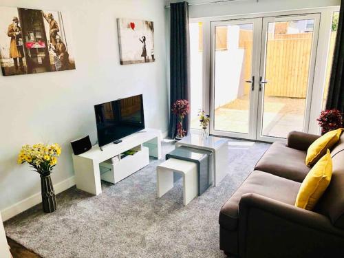 a living room with a couch and a tv at Centrally situated house plus private parking in Cheltenham